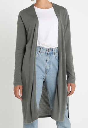 Person wearing a long, open-front gray cardigan, white t-shirt, and light blue high-waisted jeans against a plain background.