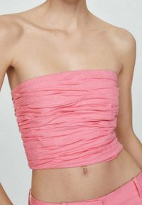 Top bustier froncé en tissu rose clair, avec des plis texturés et une coupe ajustée, se terminant juste au-dessus de la taille.