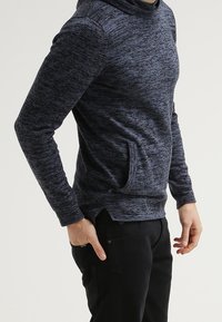 Navyblå hoodies med en strukturerad, marmorliknande mönster, känguruficka och sidöppningar, tillverkad av mjukt, stretchigt tyg.