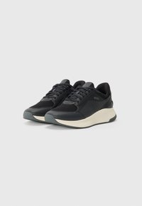 Black athletic sneakers with mesh and leather materials, featuring a textured design, contrasting white midsole, and grey outsole.