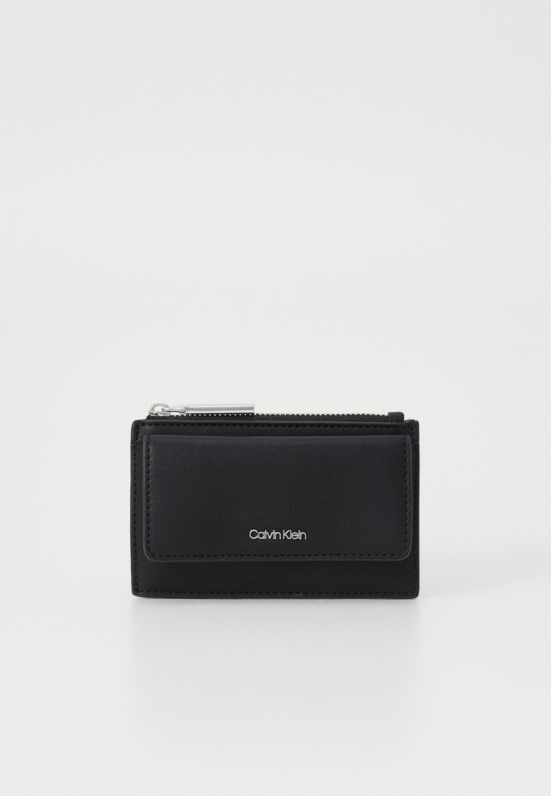 Svart läderplånbok med dragkedjestängning, framficka och silverdetalj med logotyp. Slät textur, rektangulär form, kompakt design.