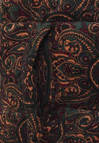 Tessuto a costine con un motivo paisley nei colori verde scuro, arancione e bordeaux; presenta una cerniera visibile e una superficie dal texture marcata.