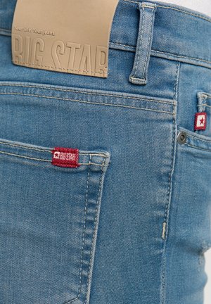 Heledad sinine teksapüksid, mille vööna on tekstuuriga nahkplekk, millel on silt "BIG STAR". Omab punaseid logo silte ja klassikalist viit taskut.