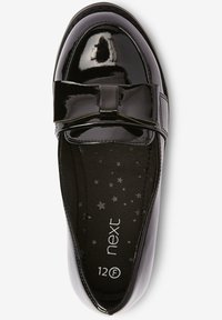 Sort laklædersflad sko med sløjfedetalje, rundet tå og stjernemønstret indersål. Str. 12F med en glat, blank finish.