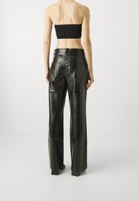 Zwarte faux leren broek met een krokodillenstructuur, featuring een hoge taille en brede, rechte pijpen. Achterzakken zichtbaar.