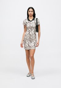 Φόρεμα με κοντά μανίκια και σχέδιο φιδιού σε μπεζ και μαύρο, με μαύρο γιακά. Λείος υφασμάτινος χαρακτήρας με εφαρμοστή γραμμή. Ασημένια παπούτσια με λουράκι.