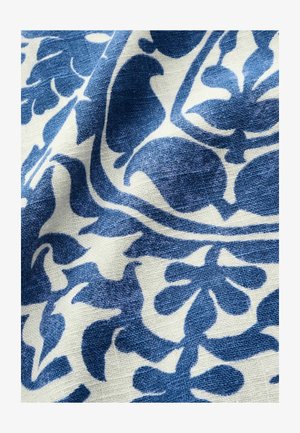 Patterned fabric featuring blue floral motifs on a white background, with a textured weave and intricate design details.