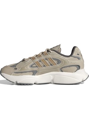 Beiger und grauer Sneaker mit niedrigem Schaft, Mesh-Einsätzen, drei beigen Streifen an der Seite, Schnürverschluss und dicker weißer Sohle.