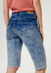 Denimshorts met een verloop van lichtblauw naar middelblauw, een gegarneerde zoom en twee achterzakken met gestikte details. Leren merkembleem aan de taille.