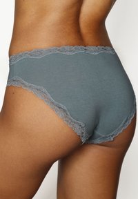 Tumši pelēki kokvilnas hipster apakšbikšu ar mežģīņu apdari jostasvietā un kāju atverēs, ar gludu tekstūru un bez redzamām detaļām.