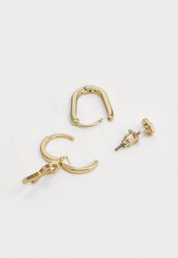 Ensemble de boucles d'oreilles dorées comprenant un anneau rectangulaire, un anneau incurvé et une conception de puce, tous avec une finition métallique brillante.