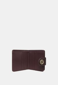 Portafoglio in pelle bordeaux con texture liscia, diversi slot per carte e una chiusura tonda in tonalità oro con un emblema decorativo.
