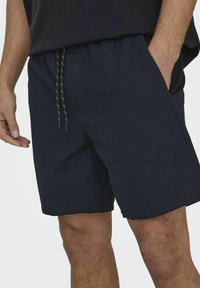 Shorts bleu marine en tissu léger, dotés d'une taille élastique avec cordon de serrage et de poches latérales, arrivant au-dessus du genou.
