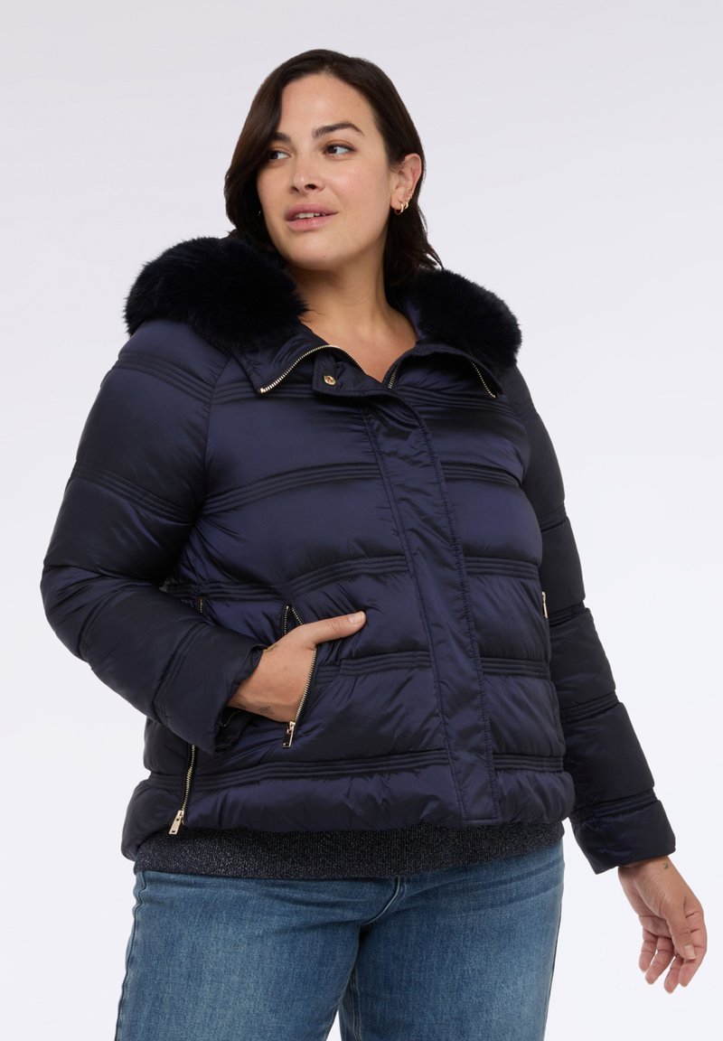 Marineblaue Steppjacke mit Kunstfellkragen, horizontalen Nähten, Reißverschlusstaschen und goldenem Beschlag, mit einer warmen, glatten Außenseite.