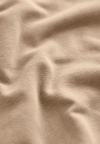 Material bej deschis cu o suprafață netedă, ușor texturată, prezentând cute și pliuri delicate pentru un aspect moale și drapat.