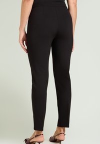 Pantaloni neri aderenti con una texture liscia, design a gamba dritta e vita media. Caratterizzati da cuciture nascoste e una finitura pulita alle caviglie.