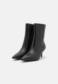 Botas de tornozelo pretas em couro liso, com bico apontado e salto fino. Design elegante com uma silhueta fluida e acentos mínimos.