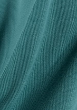 Turquoise katoenen stof met een geribbelde textuur, met verticale lijnen en een glad, zacht oppervlak. Schaduwen en hooglichten zorgen voor diepte.