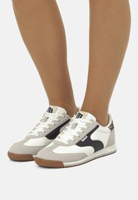 Weiße und graue Sneakers mit schwarzen Akzenten, aus Wildleder und Leder, runde Zehenform, flache Gummisohle und Schnürsenkel. Goldenes Logodetail an der Zunge.