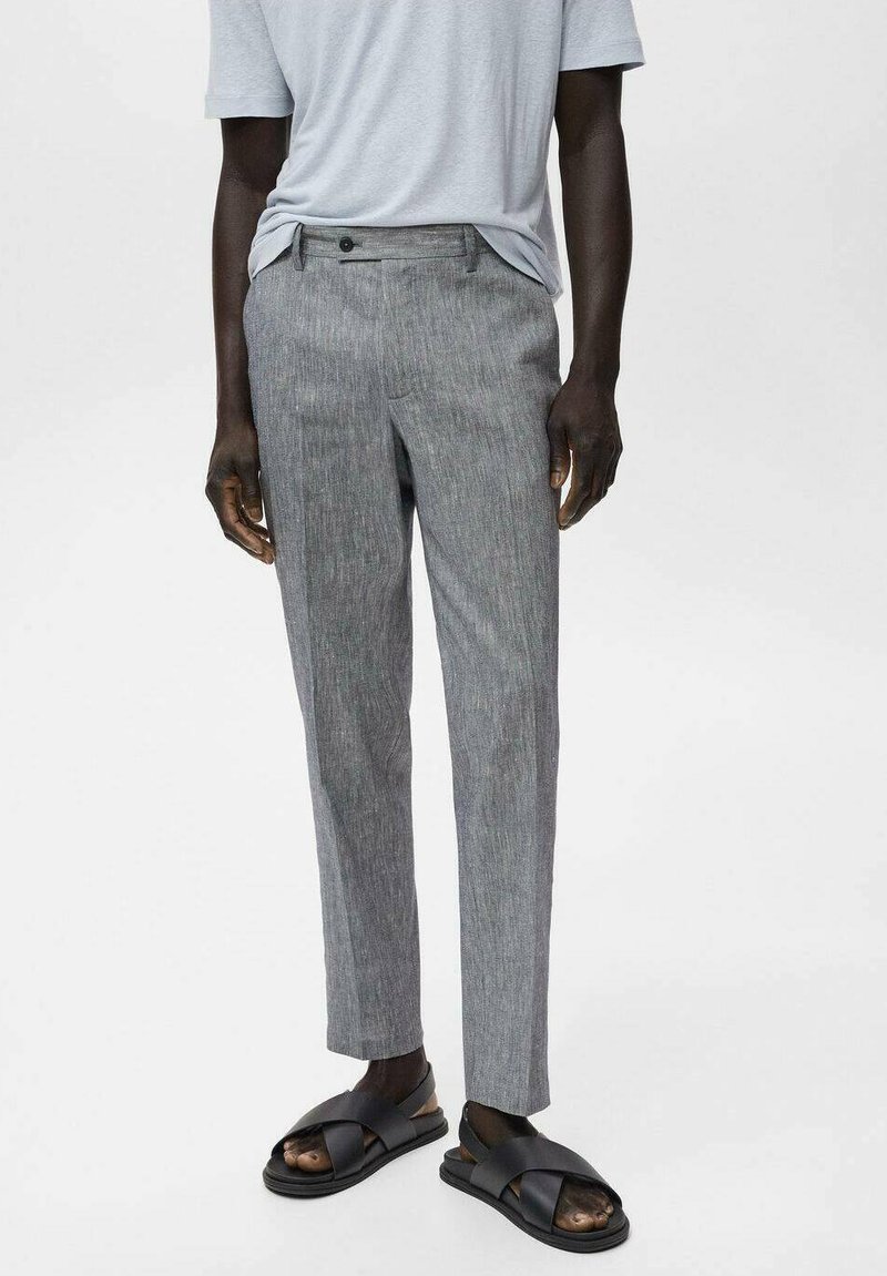 Grå, strukturerade byxor med skräddarsydd passform, med dragkedja och knappstängning. Kombination med svarta slip-on sandaler.