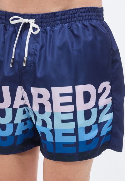 Μπλε μαγιό βερμούδα με ελαστική μέση, λευκό κορδόνι και μεγάλο τύπωμα "JABRED" σε αποχρώσεις από ροζ σε ανοιχτό μπλε. Λείο, ελαφρύ ύφασμα.