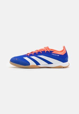 Blue soccer shoes feature a textured upper, white stripes, and orange accents. The sole is gum-colored with a distinctive grip pattern.