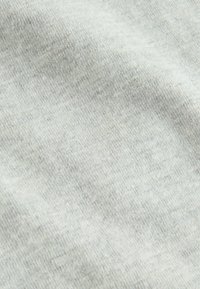 Jasnoszara tkanina o miękkiej, gładkiej teksturze, z delikatnymi wzorami dzianinowymi i niewielkimi różnicami w odcieniu, sugerująca swobodny, komfortowy materiał.