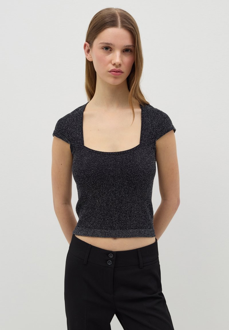 Top negro de manga corta con escote cuadrado. Tejido de punto texturizado con un ligero brillo. Diseño ajustado, combinado con pantalones negros.