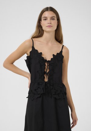 Black top with ruffled edges, adjustable ties at the front, and thin straps. Fabric has a smooth texture, with a relaxed fit silhouette.