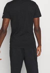 Černé pánské tričko s krátkým rukávem z bavlny s kulatým výstřihem. Obsahuje nenápadné logo na levém rameni. Hladký materiál a přiléhavý střih.