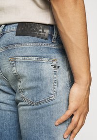 Jeans de mezclilla azul con un corte regular, que presentan una etiqueta de piel en la cintura y costuras visibles en los bolsillos traseros.