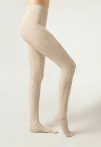 Beige, ribbede strømpebukser med kabelstrikdesign. Glat tekstur, tætsiddende facon og høj talje, der dækker benet til anklen.