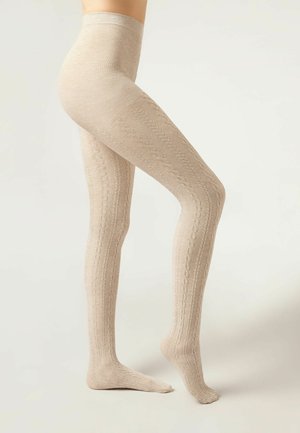 Collants beiges à côtes avec un motif en maille cablée. Texture lisse, forme ajustée et taille haute, couvrant la jambe jusqu'à la cheville.
