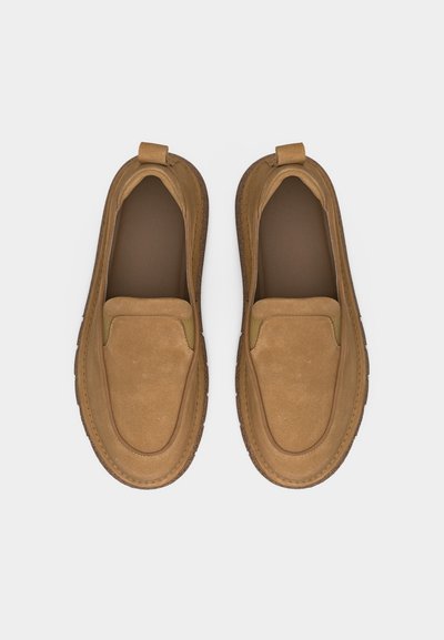 Ζευγάρι ταμπά μοκασίνια από σουέντ χωρίς κορδόνια με στρογγυλεμένες μύτες και ραμμένα διακοσμητικά, σε λευκό φόντο, απεικονιζόμενα από πάνω.
