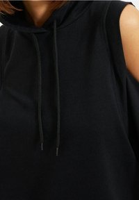 Zwarte mouwloze hoodie van een zachte katoenmix, met een brede hals, een capuchon met trekkoord en onbedekte schouders voor een ontspannen pasvorm.