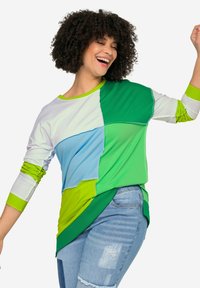 Top de manga larga colorido que presenta un patchwork en tonos verde, azul y blanco. Tejido suave con un corte relajado y un dobladillo curvado.