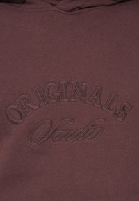 Mørkerød hættetrøje med broderet "ORIGINALS Studio" tekst i en mørkere tråd. Lavet af blødt stof, med snore i hætten og en afslappet pasform.