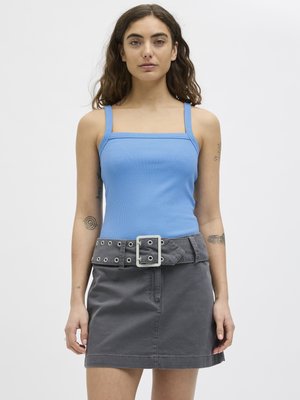 Helles blaues, geripptes Tanktop mit quadratischem Ausschnitt, kombiniert mit einem grauen Jeansrock, der große Schnallen und Ösen als Akzente hat.