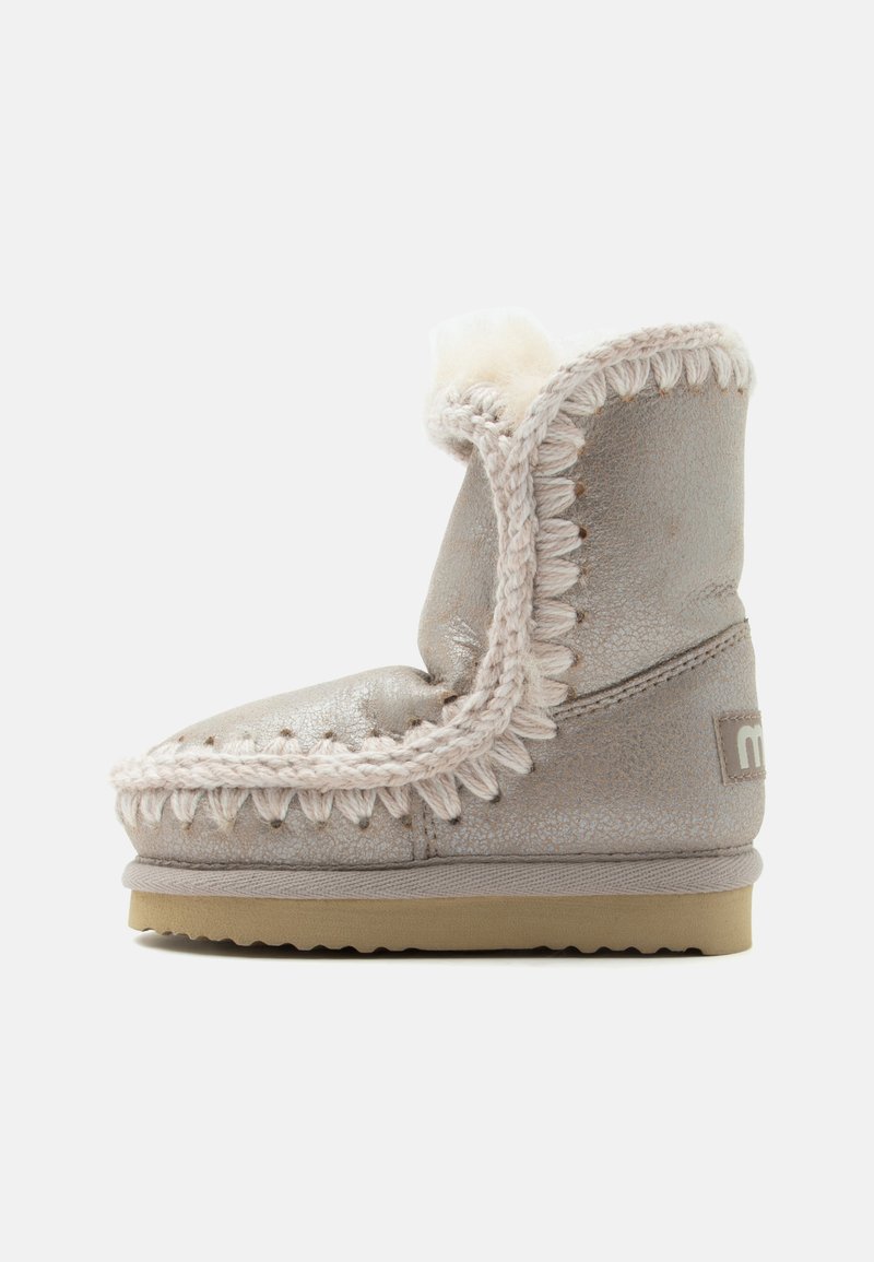 Botte d'hiver grise style mocassin avec une épaisse couture crème, une doublure en peau de mouton et une semelle en caoutchouc beige, vue de côté.