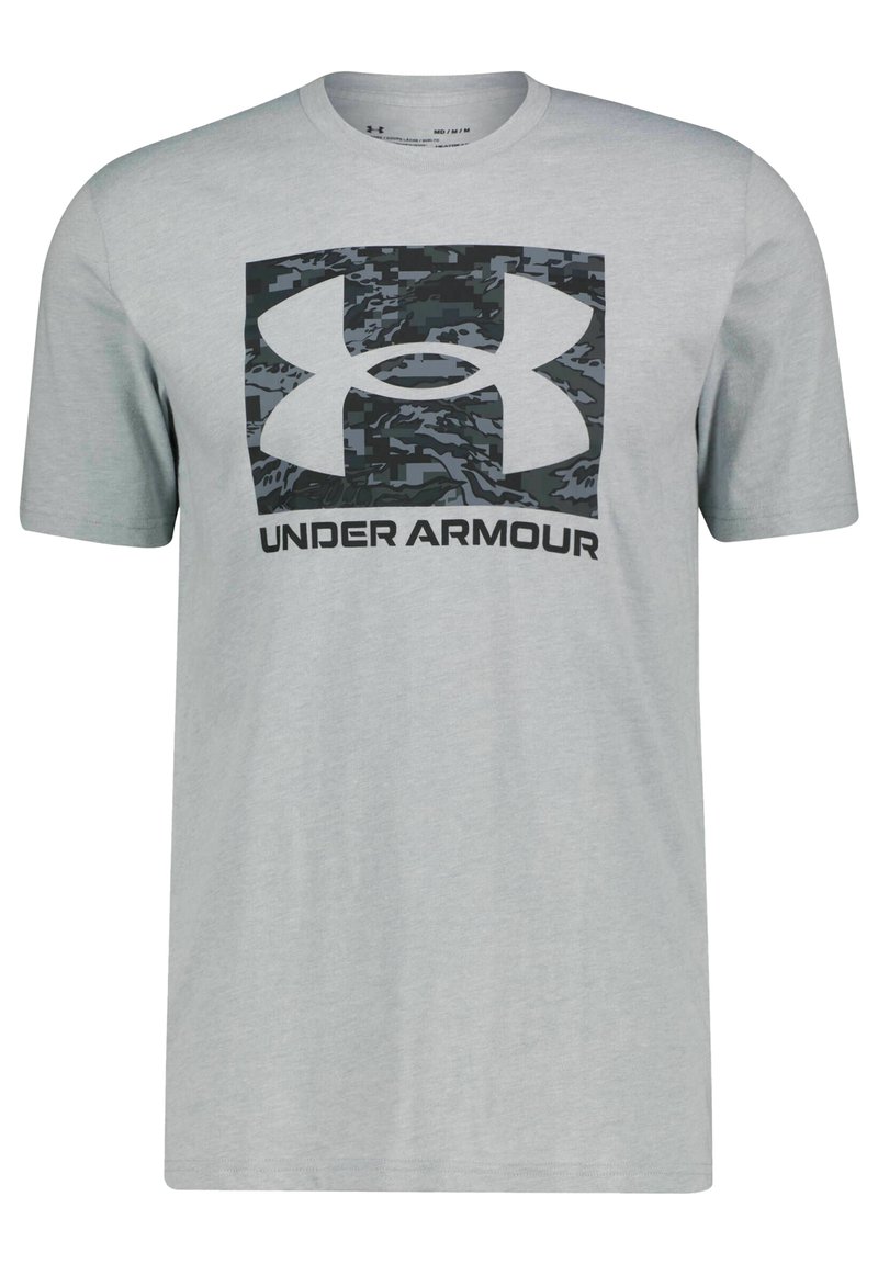 Camiseta gris de manga corta hecha de algodón, con un logo de camuflaje en negro y gris de Under Armour en un gráfico rectangular en la parte frontal.