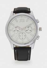 Montre chronographe avec un boîtier en métal argenté, un cadran texturé blanc, un bracelet en cuir noir et des accents argentés. Chiffres arabes présents.