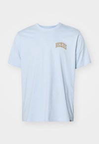 Világoskék pamut póló rövid ujjal, amelyen elöl egy kis, ívelt "DICKIES" logó található narancssárga színben. Normál szabás.