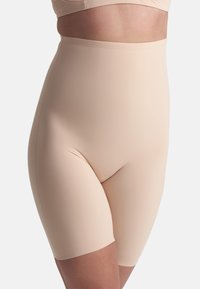 Shorts beige a vita alta indossati da una persona, che arrivano a metà coscia, progettati per modellare il corpo in modo uniforme.