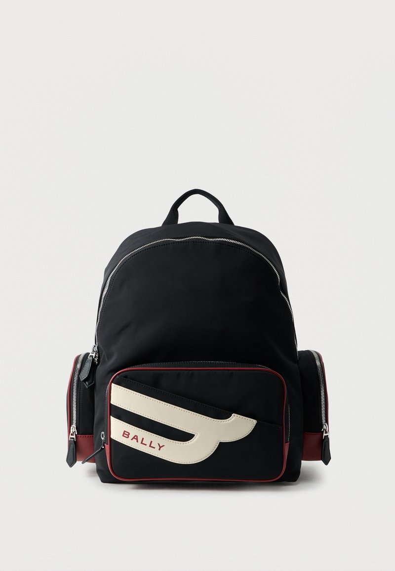 Sac à dos noir Bally avec grande poche avant ornée d'un logo blanc et deux compartiments latéraux zippés sur fond blanc.