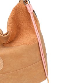 Borsa in suede marrone chiaro e pelle testurizzata con cordoncino rosa e dettagli in anello metallico argentato, mostrata in primo piano su sfondo bianco.