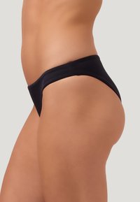 Schwarzer Bikiniunterteil mit niedrigem Bund, ausgestattet mit einer glatten Textur und minimaler Abdeckung, das ein einfaches Design präsentiert.