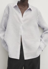 Lätt, randig skjorta med knappar i vitt och mjukt lavendel med avslappnad passform, lång ärm och klassisk kragsdesign.