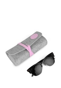 Šedý pouzdro na sluneční brýle s růžovým popruhem a logem; černé sluneční brýle s ostrými rámy a tmavými skly leží vedle něj.