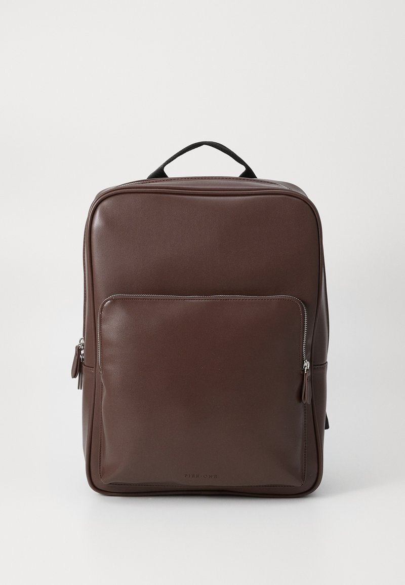 Brown leather backpack with a smooth finish, rectangular shape, top handle, and a front zip pocket. Subtle logo near the bottom.