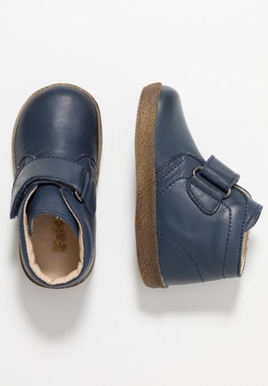 Scarpe in pelle blu navy con punta arrotondata, cinturino in velcro e suola marrone testurizzata. Finitura liscia con dettagli di cucitura e rivestimento interno.
